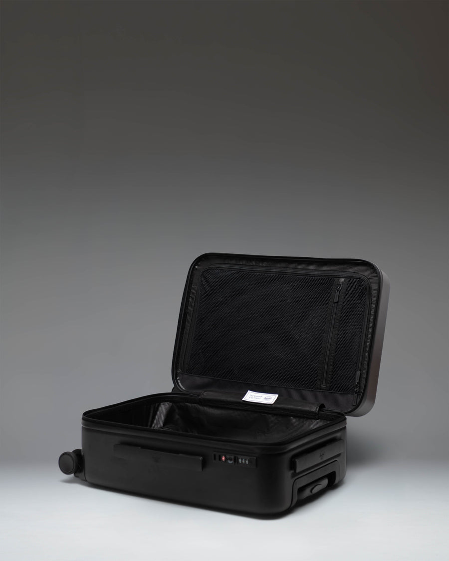 Black Herschel Heritage Hardshell Large CarryOn Luggage shown from a side angle, highlighting its durable exterior and sleek design.