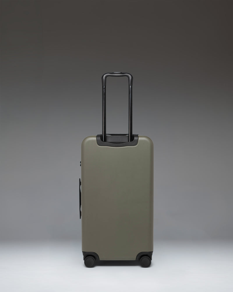 Herschel Heritage Hardshell Medium Luggage in Ivy Green shown from the side, highlighting its sleek design and durable construction.