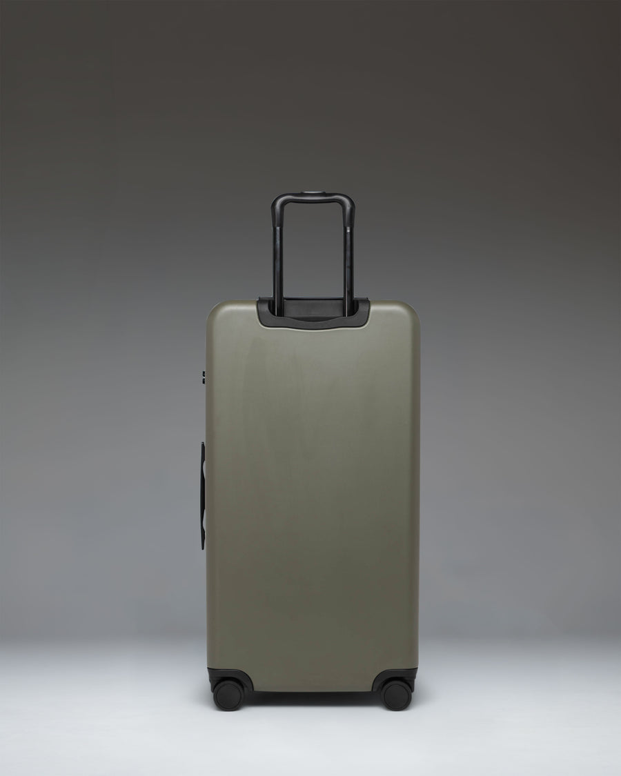 Herschel Heritage Hardshell Large Luggage in Ivy Green. Front view of the large green rolling suitcase with top and side handles.