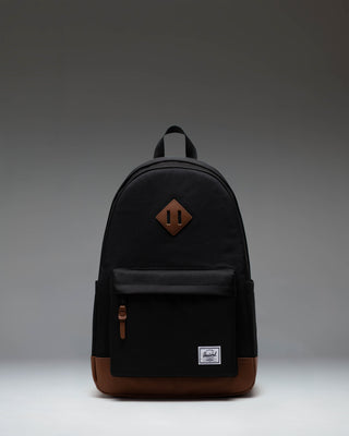 Herschel Heritage Backpack in Black with a Tan brown diamond accent and bottom panel, shown from the front on a white background.