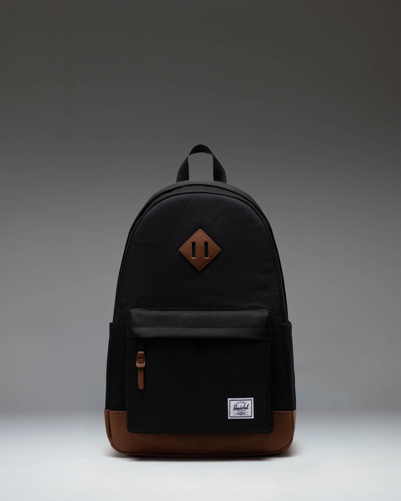 Herschel Heritage Backpack in Black with a Tan brown diamond accent and bottom panel, shown from the front on a white background.