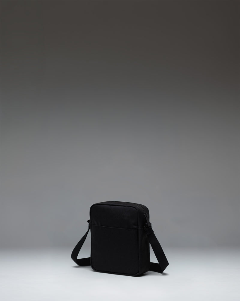 Herschel Heritage Crossbody bag in black, shown from an angled perspective highlighting the front zipper pocket and adjustable strap.