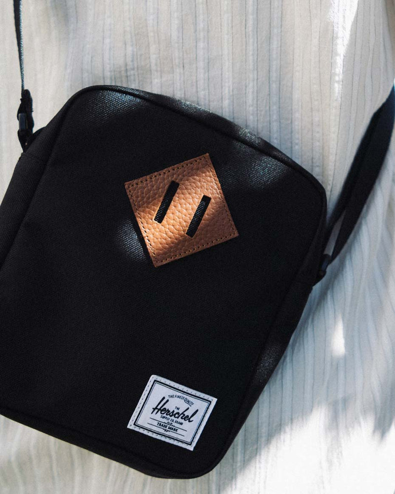 Herschel Heritage Crossbody Bag. A boxy style with a signature diamond detail, an adjustable over-the-shoulder strap, and zippered closure.