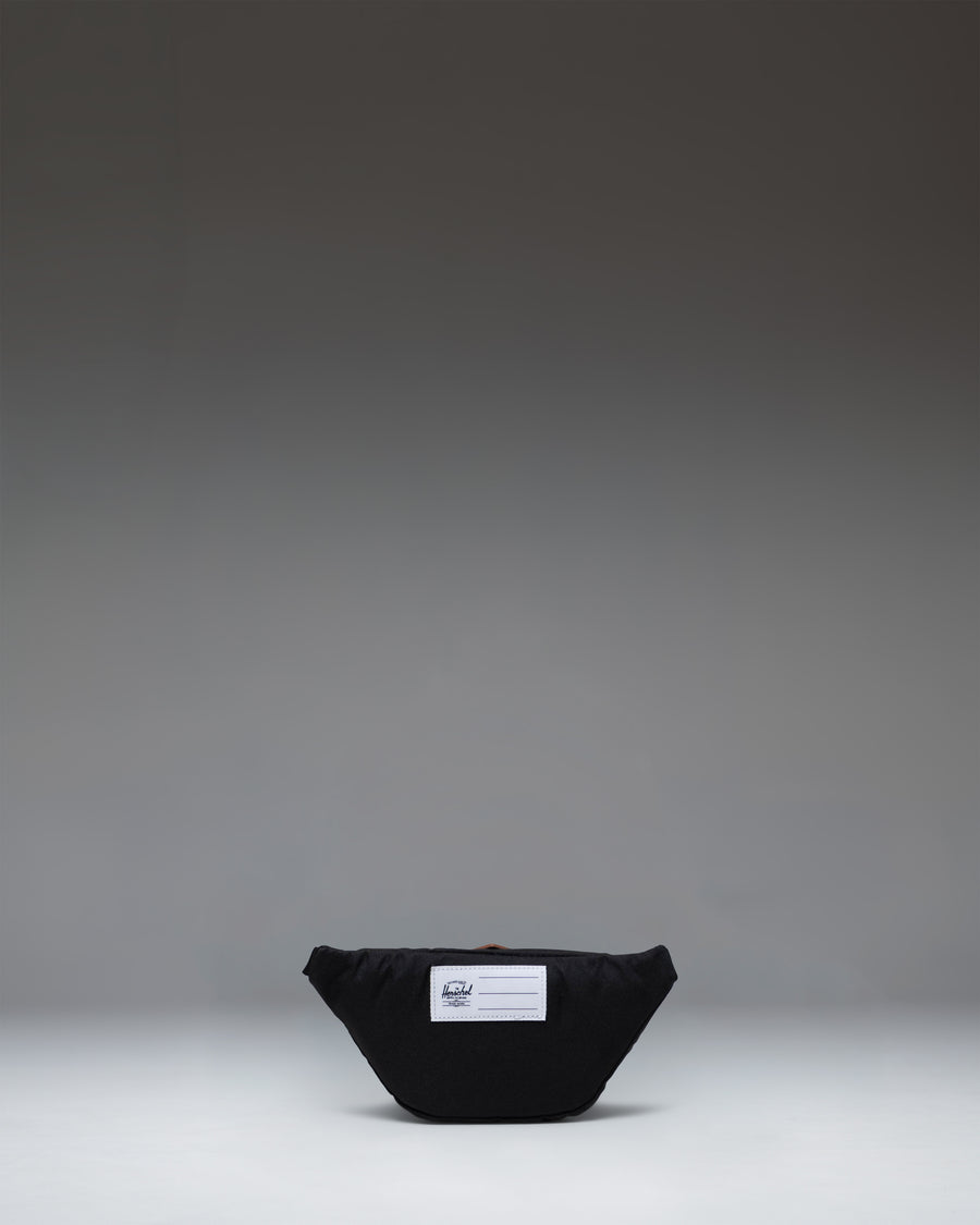 Black Little Herschel Heritage Hip Pack shown from the back, featuring an adjustable webbed strap with a plastic buckle clip.