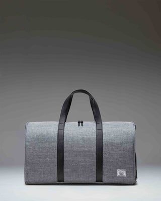 Herschel Novel Duffle bag in Raven Crosshatch grey with black carrying handles and a removable shoulder strap.