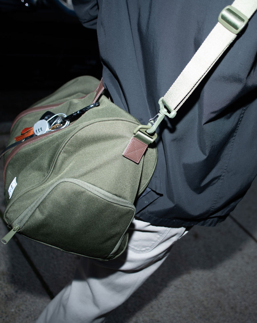 Herschel Novel Duffle bag in a multicolored abstract pattern featuring blue, orange, brown, and green blocks.