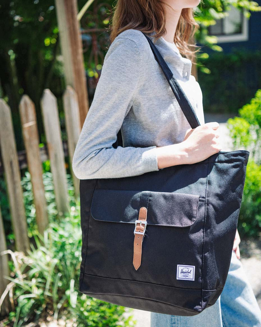Herschel Supply Co. Retreat Tote in a multicolored camouflage pattern with slim top handles, a front pocket, and a magnetic strap buckle closure.