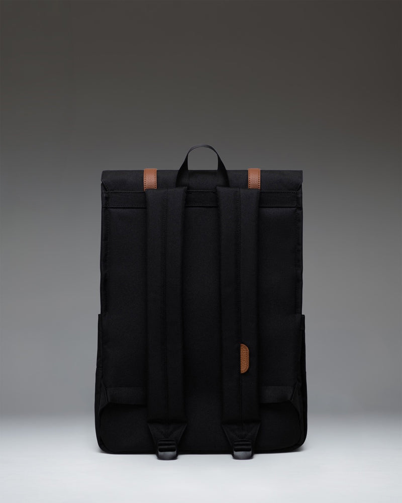 Black Herschel Supply Co. Survey Backpack featuring a minimalist design, front flap with magnetic strap closures, and padded shoulder straps.