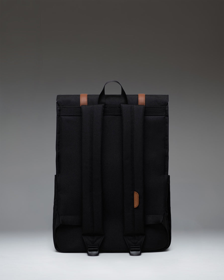 Black Herschel Supply Co. Survey Backpack featuring a minimalist design, front flap with magnetic strap closures, and padded shoulder straps.