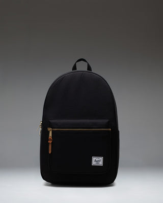 Front view of the classic Herschel Supply Co. Settlement Backpack in black, featuring a front pocket and exposed gold zippers.