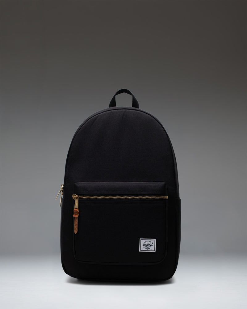 Front view of the classic Herschel Supply Co. Settlement Backpack in black, featuring a front pocket and exposed gold zippers.