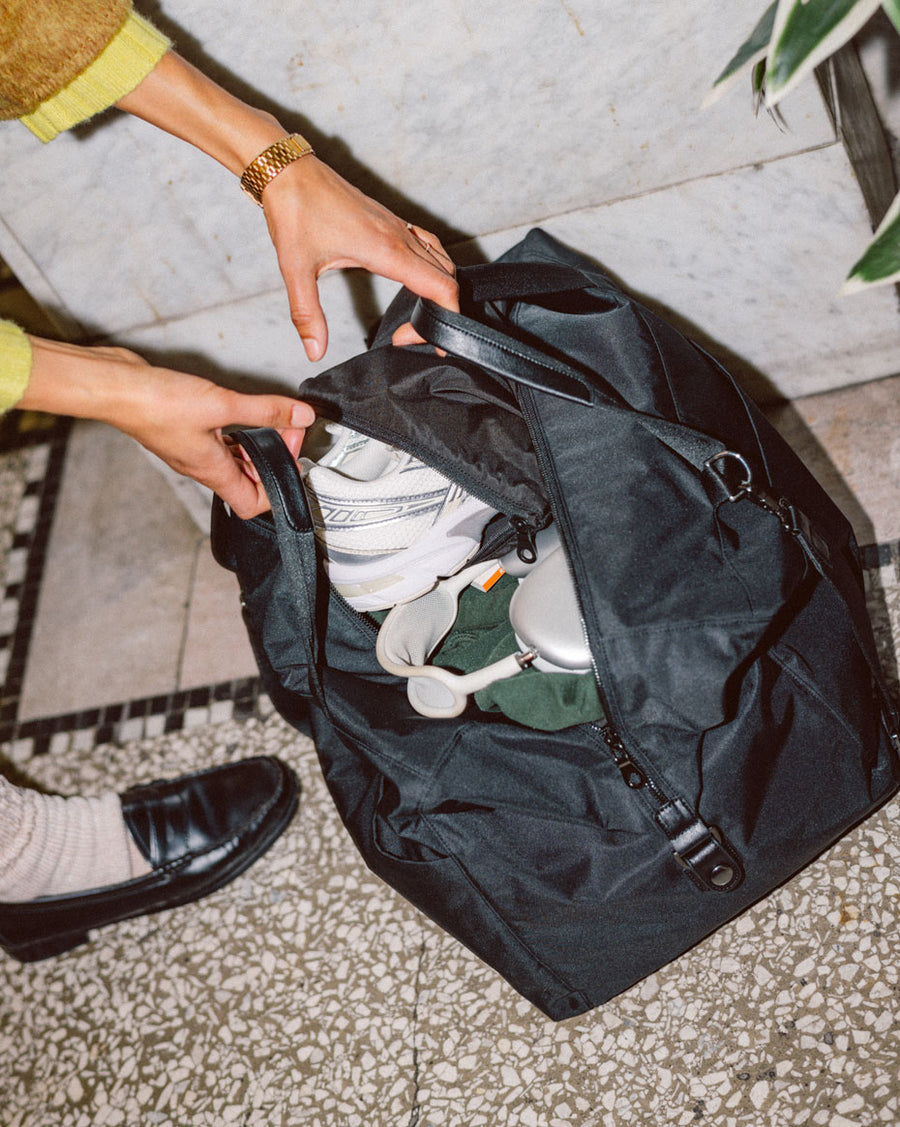 A collection of Herschel Supply Co. x Realtree essential bags and apparel neatly arranged to showcase the APX camouflage pattern.