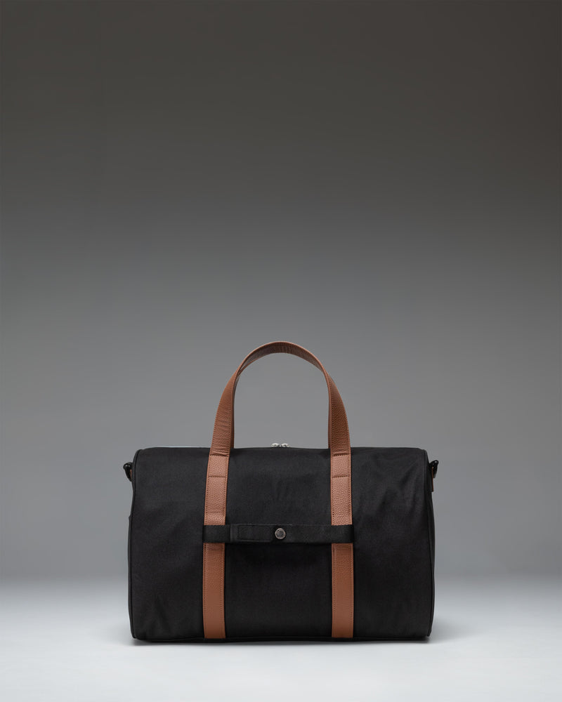 Herschel Novel Carry On Duffle bag in solid black, featuring dual top handles and a removable shoulder strap for travel.