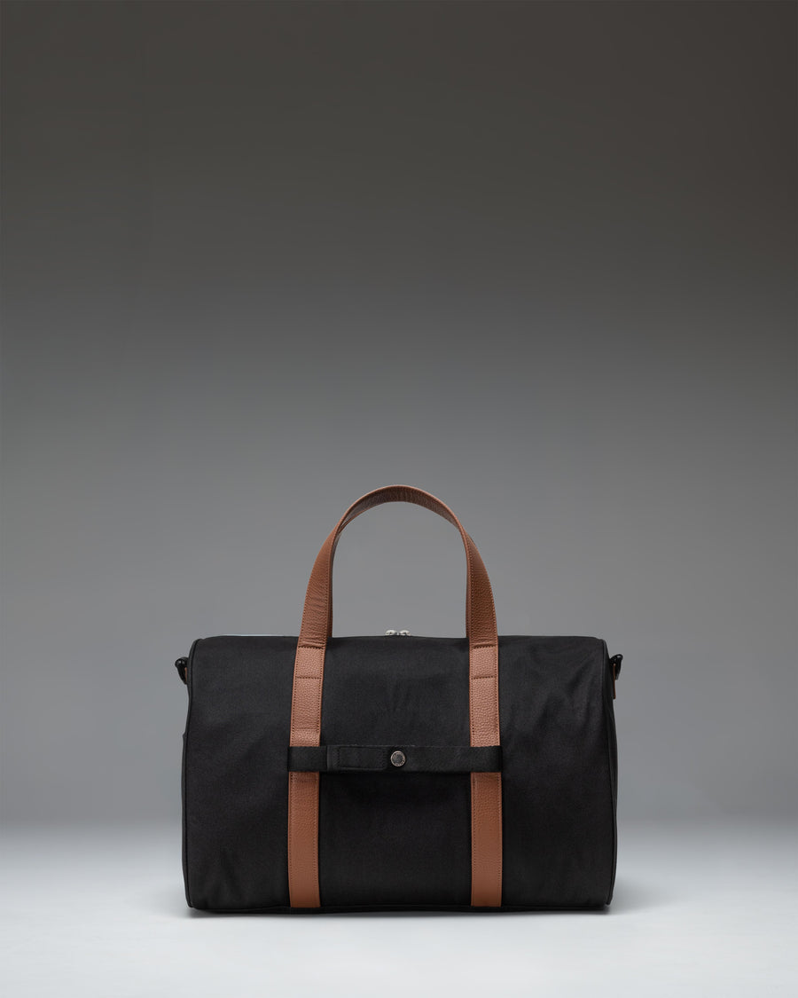 Herschel Novel Carry On Duffle bag in solid black, featuring dual top handles and a removable shoulder strap for travel.