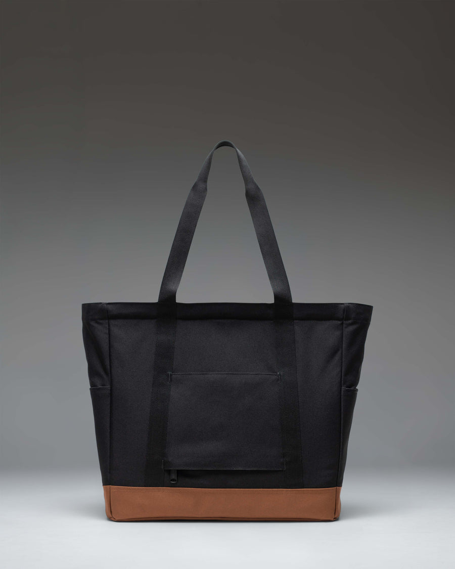 Herschel Supply Co. Heritage Tote in black with saddle brown top handles and a diamond detail patch on the front.
