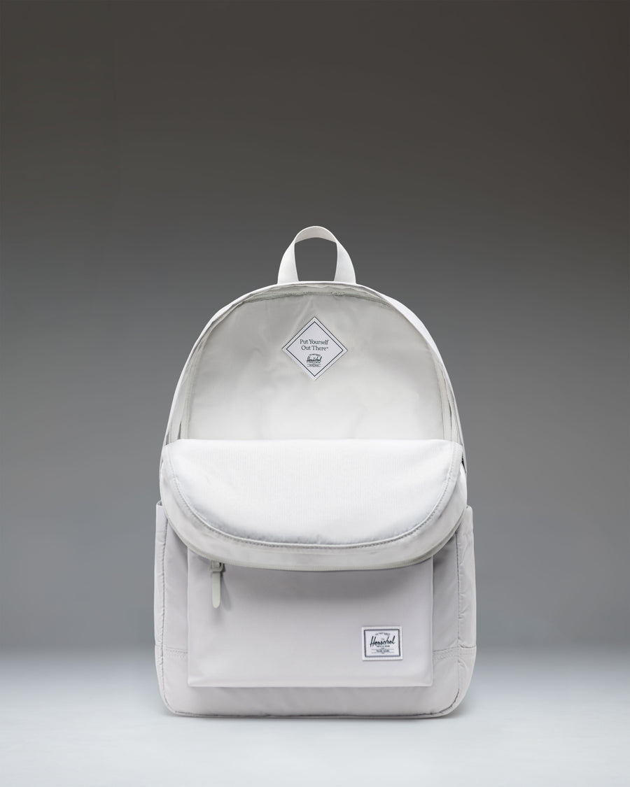 Herschel Supply Co. Heritage collection backpack in Metal color worn by a child standing in front of a white background.