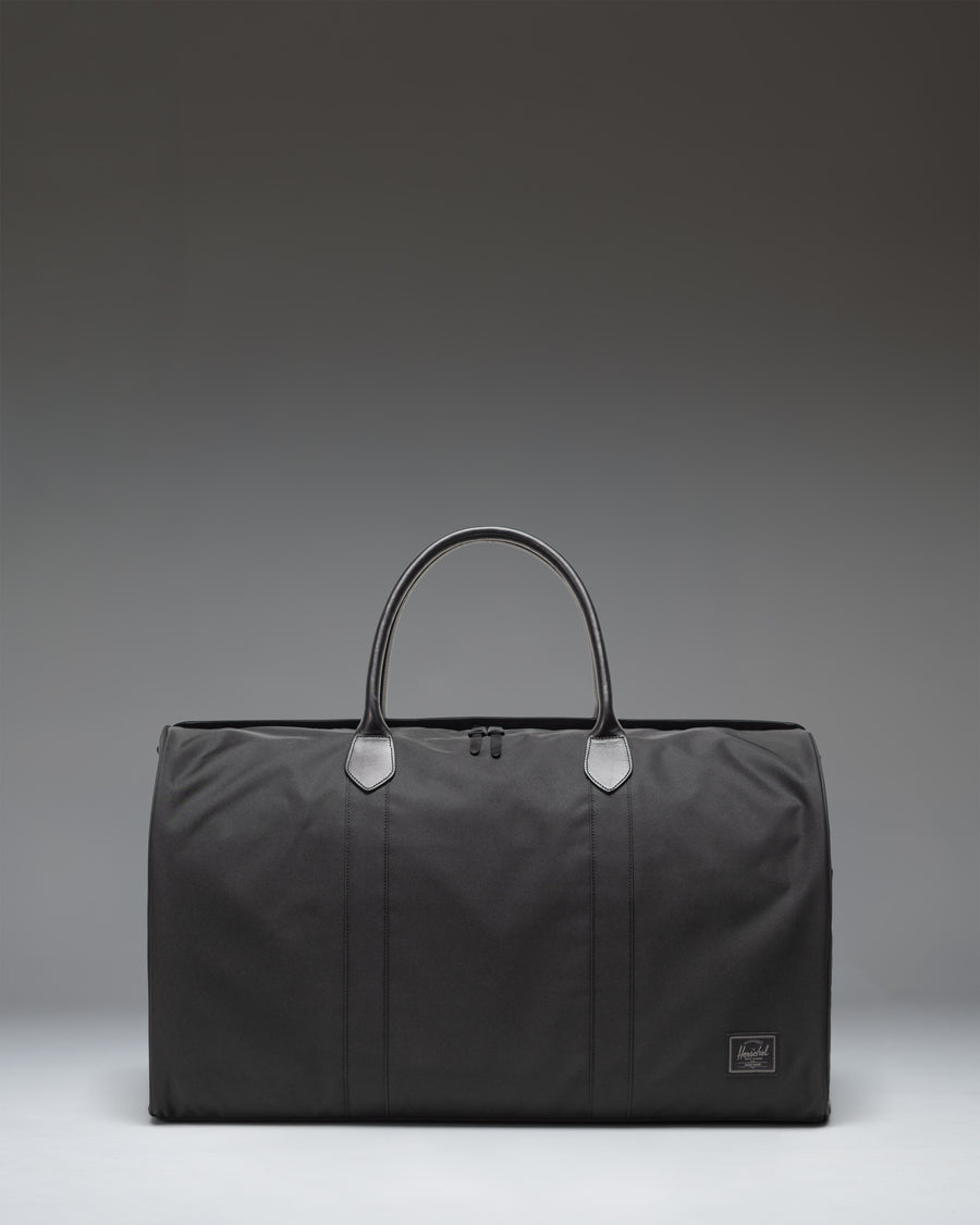 Herschel Novel Duffle bag in black, showing the clean classic design, durable handles, and signature shoe compartment.