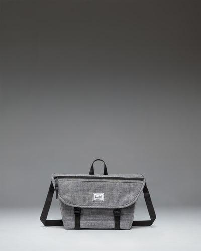 Herschel Supply Co. Cove Small Messenger bag in Raven Crosshatch grey, showing a front view with a flap closure, handle, and adjustable shoulder strap.