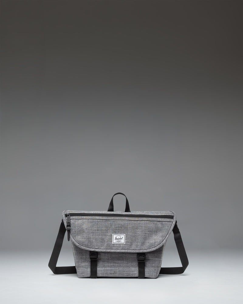 Herschel Supply Co. Cove Small Messenger bag in Raven Crosshatch grey, showing a front view with a flap closure, handle, and adjustable shoulder strap.