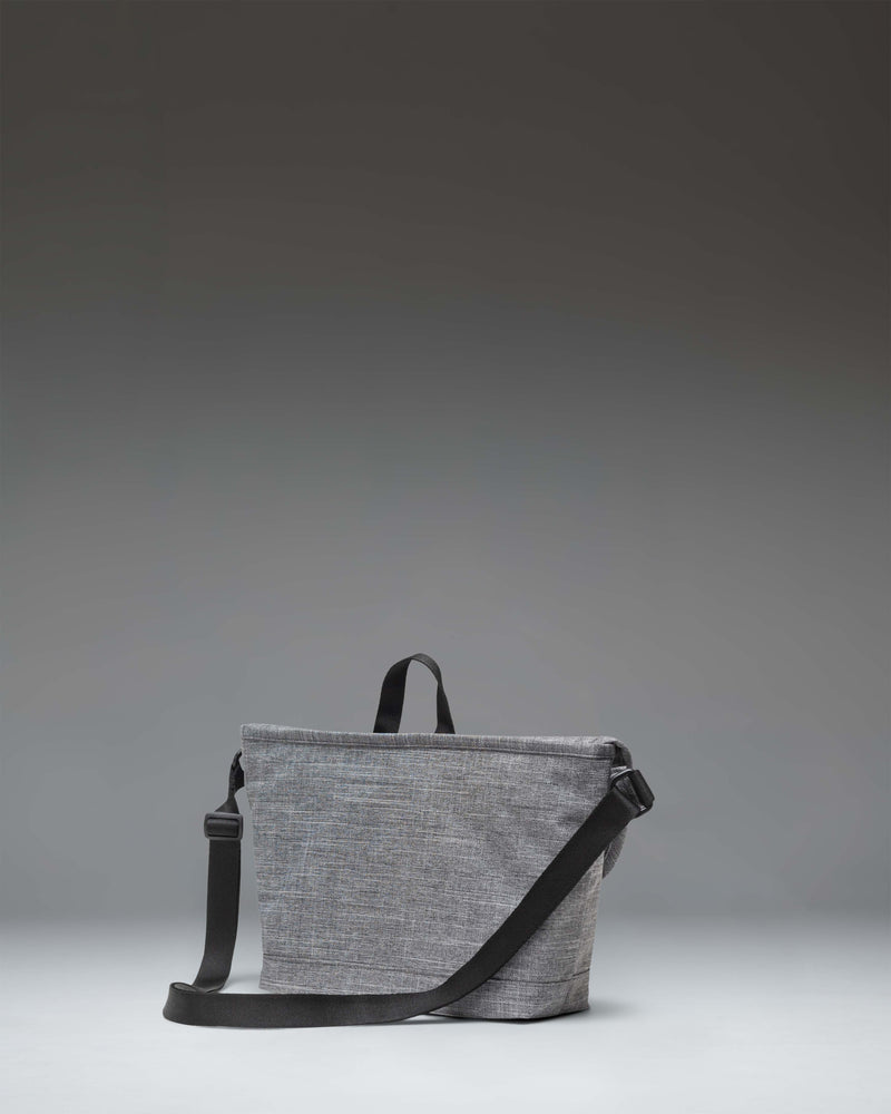 Herschel Supply Co. Cove Small Messenger bag in Raven Crosshatch grey, showing a front view with the flap closed and buckle detail.