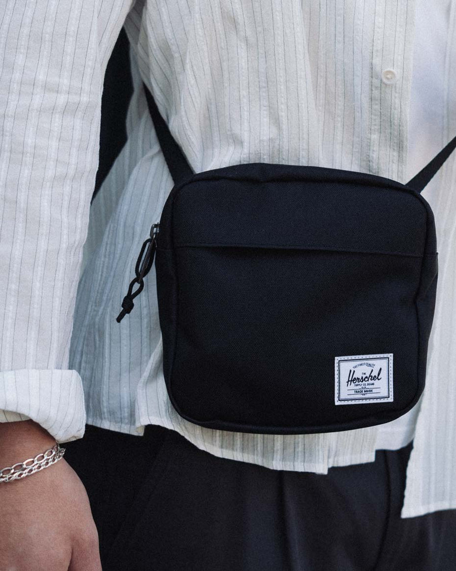 Herschel Classic Crossbody Bag featuring a multi-colored design with an adjustable shoulder strap and signature brand patch.