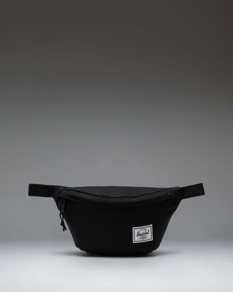 Black Herschel Classic Hip Pack featuring a main zippered compartment, front pocket, and adjustable webbed strap.
