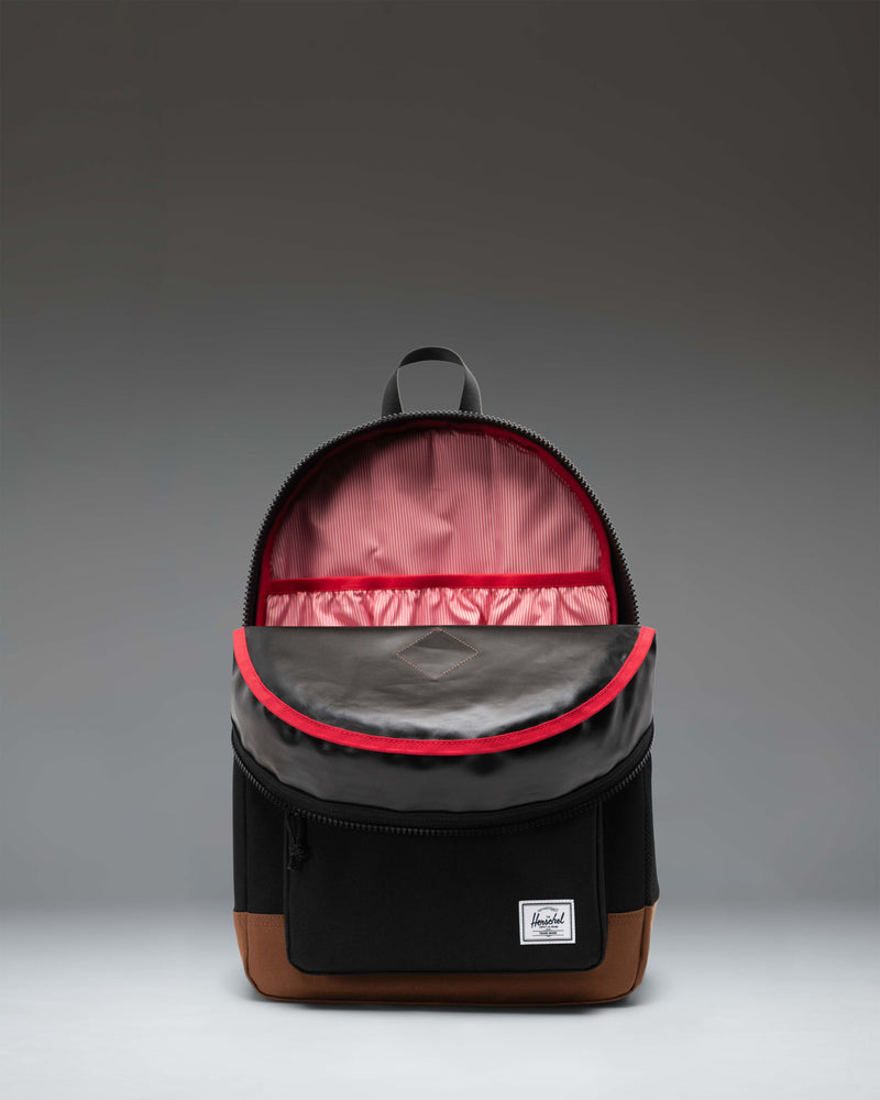Herschel Heritage Youth Backpack in Black with a Saddle Brown bottom panel, featuring a front pocket and padded shoulder straps.