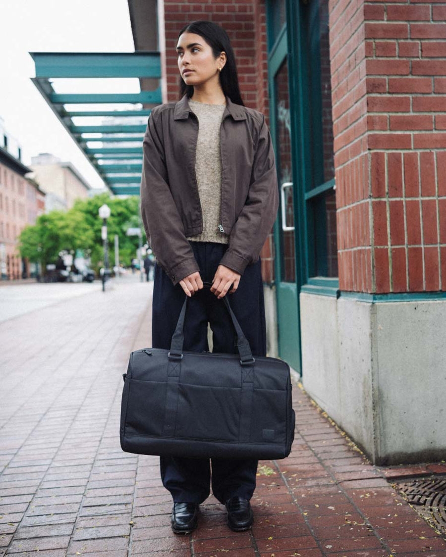 Herschel Supply Co. x Realtree limited-edition collection essential bags, apparel, and accessories arranged together in the APX camouflage pattern.