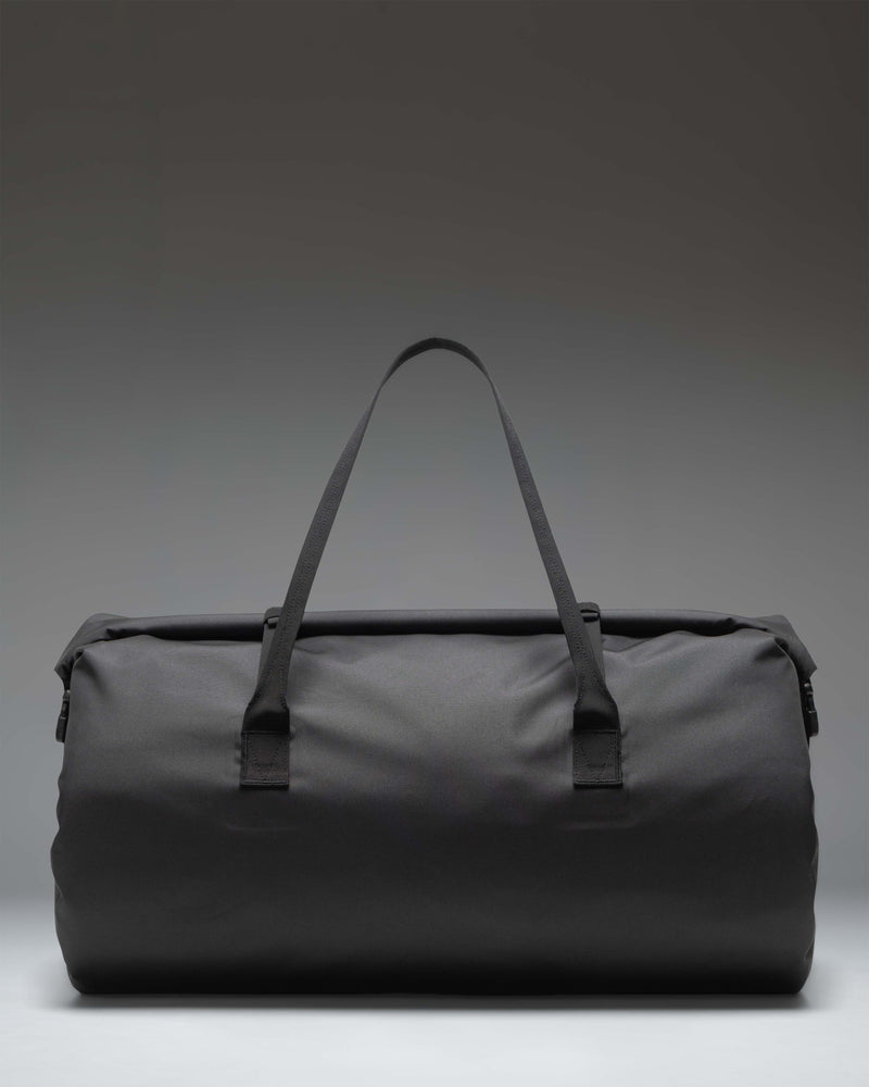 Herschel Supply Co. Dry Bag Duffle 55L in black with roll-top closure, welded seams, front zipper pocket, and top handles.