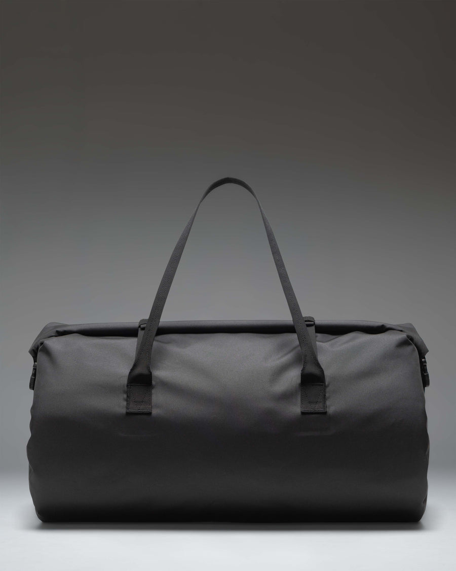 Herschel Supply Co. Dry Bag Duffle 55L in black with roll-top closure, welded seams, front zipper pocket, and top handles.