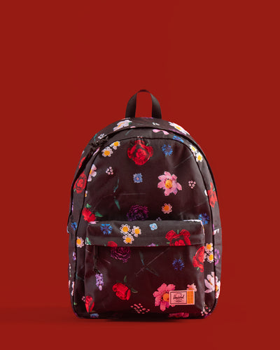 Herschel Supply Co. LEGO Classic Backpack in Falling Florals print, showing a navy blue bag covered in a colorful floral pattern with Lego brick details.