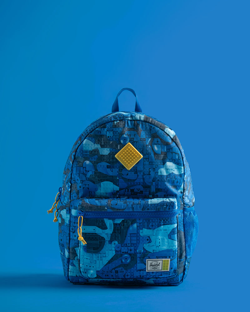 Herschel Heritage Youth Backpack in Abstract Bricks Blue, featuring a colorful LEGO brick pattern with a front storage pocket.