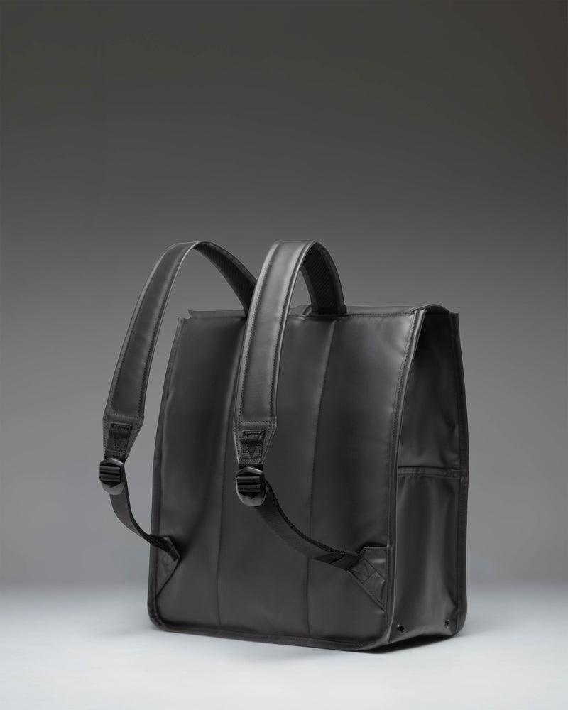 Herschel Supply Co. City Backpack in black, featuring a slim design with a single rubber strap closure and a front storage sleeve.