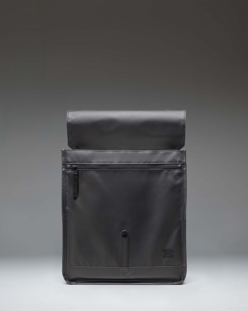 Herschel Supply Co. City Backpack in black, shown from a three-quarters front view highlighting its clean, minimalist design and single strap closure.