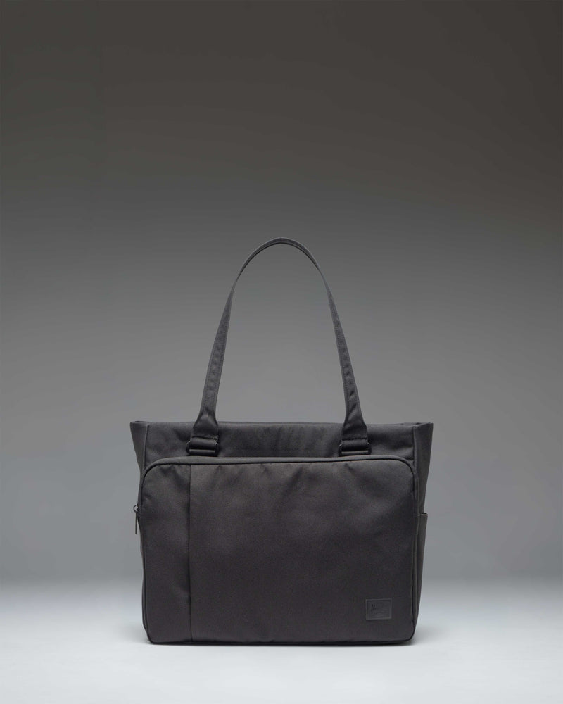 Black Herschel Supply Co. Kaslo Tote Tech bag shown from a front perspective, highlighting its clean, functional design.