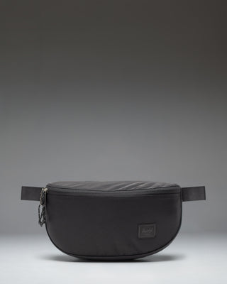 Herschel Supply Co. Kaine Hip Pack in black, featuring a front zippered pocket and an adjustable strap with a buckle.