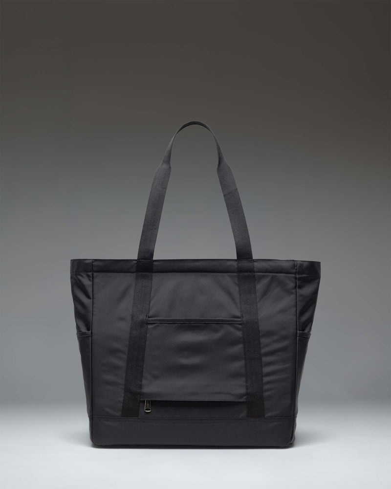 Black Herschel Supply Co. Heritage Tote bag featuring a zippered closure, top handles, front zip pocket, and signature diamond detail.