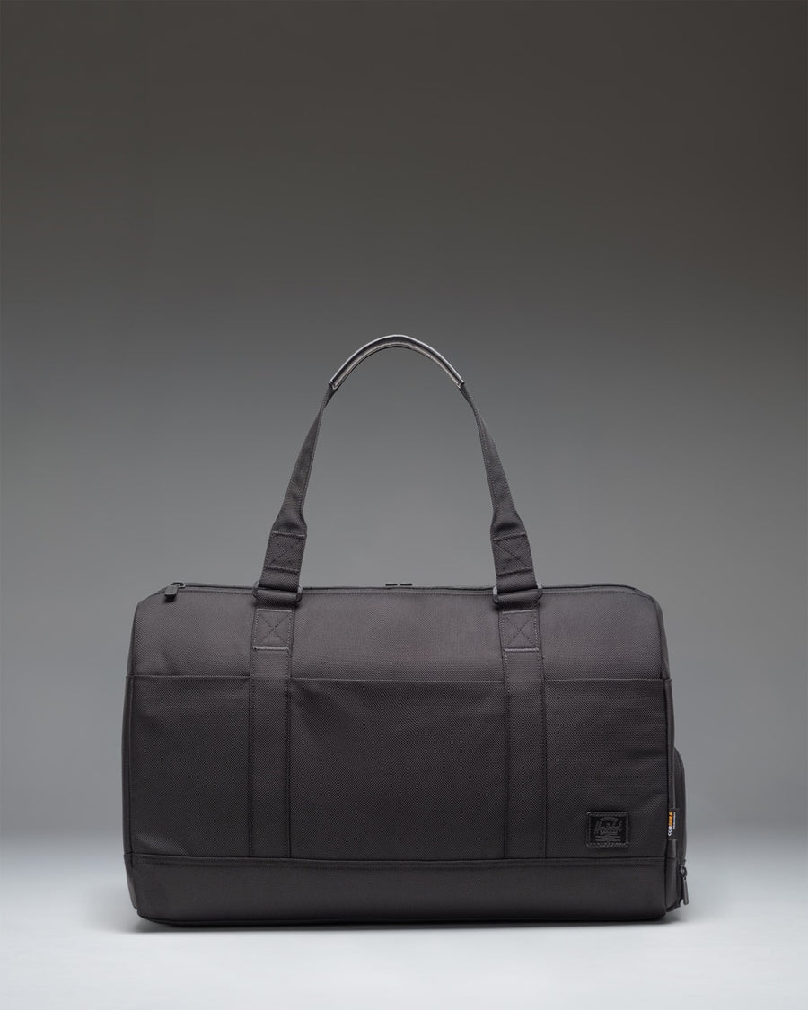 Herschel Novel Duffle Tech Cordura bag in black, showing a side view with durable handles and a clean, functional design for travel or gym use.