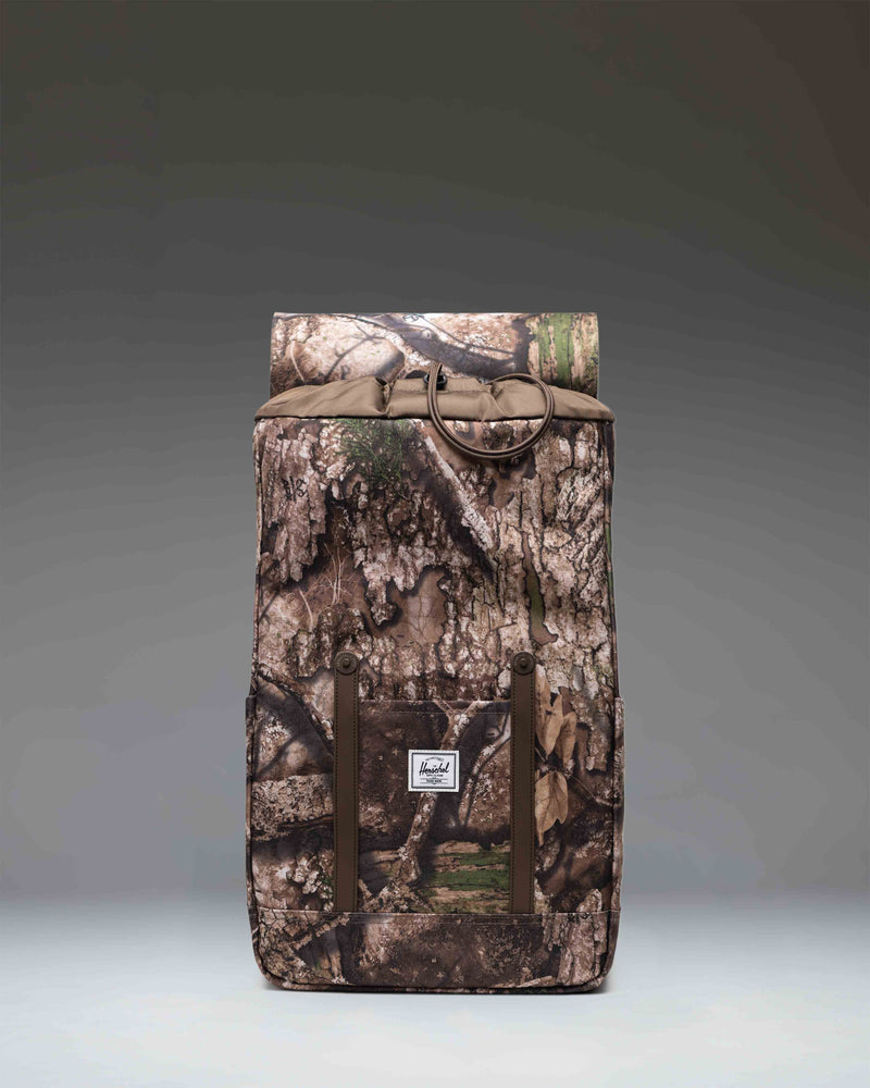 Herschel Supply Co. Realtree Retreat Backpack in Realtree APX Camo pattern, featuring dual straps and a front storage sleeve.