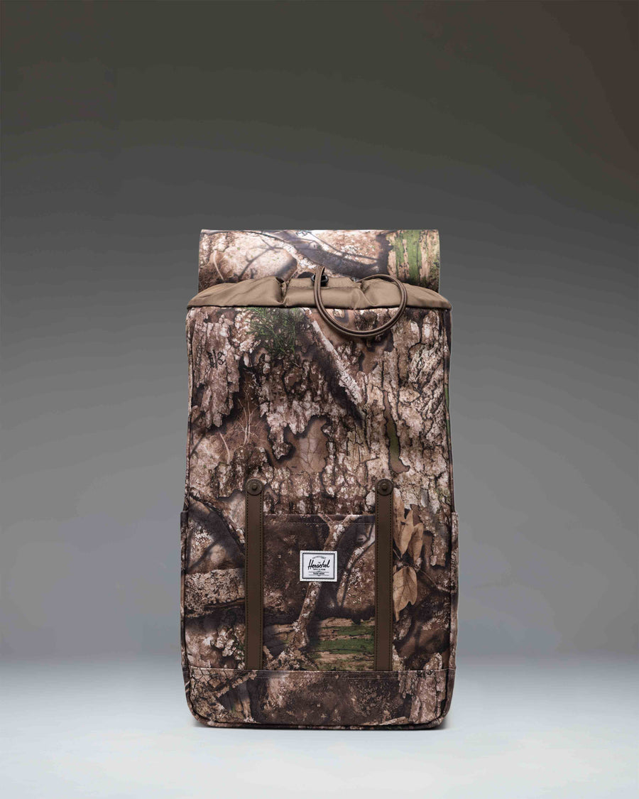 Herschel Supply Co. Realtree Retreat Backpack in Realtree APX Camo pattern, featuring dual straps and a front storage sleeve.