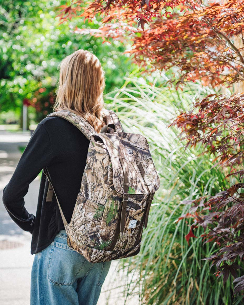 A group of Herschel Supply Co. Realtree Retreat Backpacks displayed in a variety of available colors and camouflage patterns.