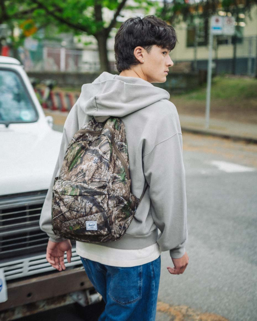 Herschel Supply Co. Realtree Rome Packable Backpack in Realtree APX Camo pattern, featuring dual water bottle pockets and a zippered front pocket.