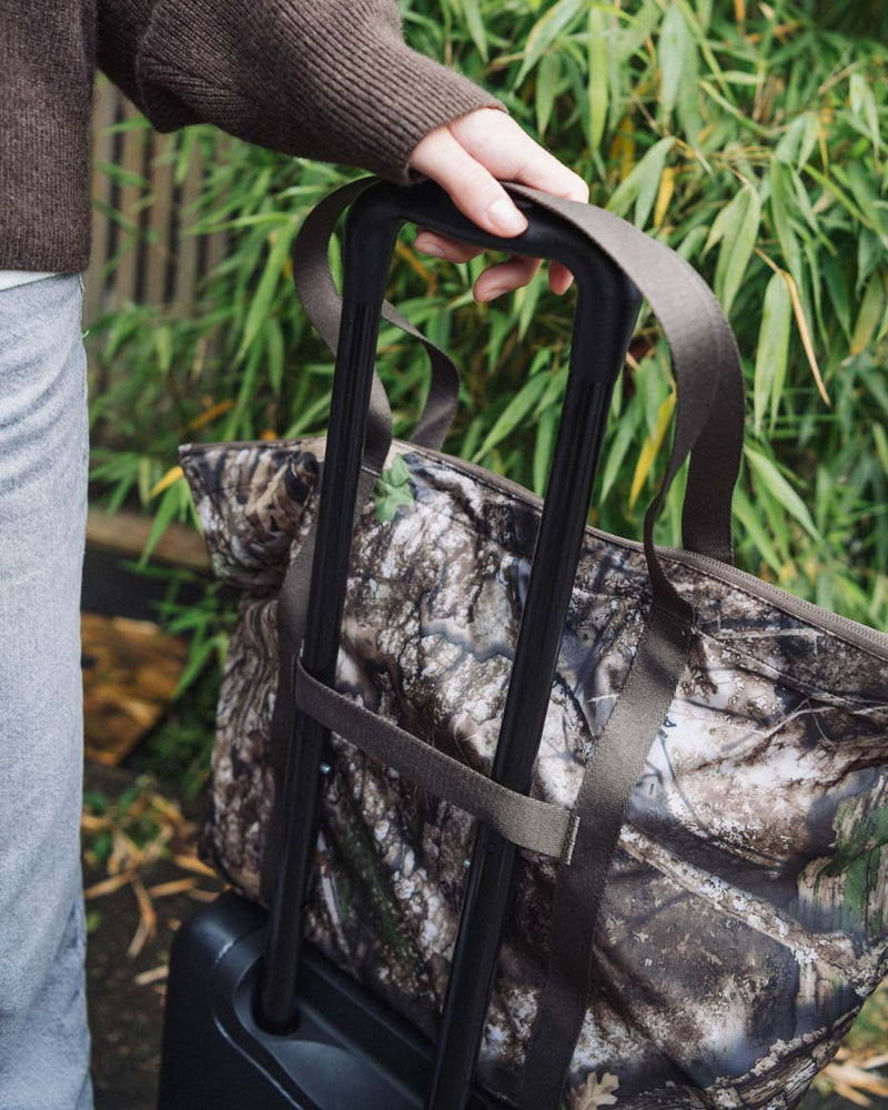 Herschel Supply Co. x Realtree limited-edition collection essential bags, apparel, and accessories arranged together in the APX camouflage pattern.
