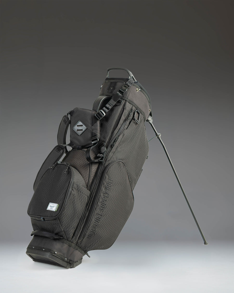 Black Herschel Watt Stand Golf Bag featuring a 5-way top organizer, multiple zippered storage pockets, and a durable fabric construction.