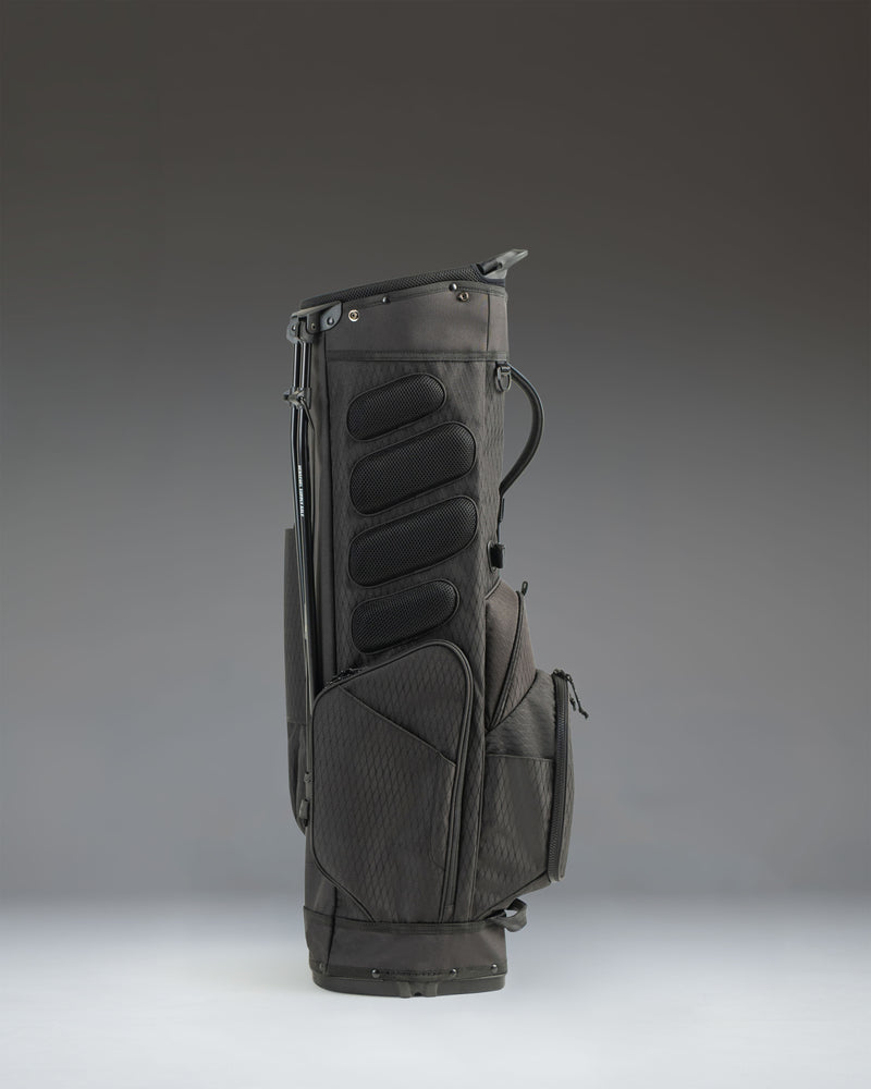 Black Herschel Watt Stand Bag showing an over-the-shoulder view of the dual carry straps and padded hip pad.