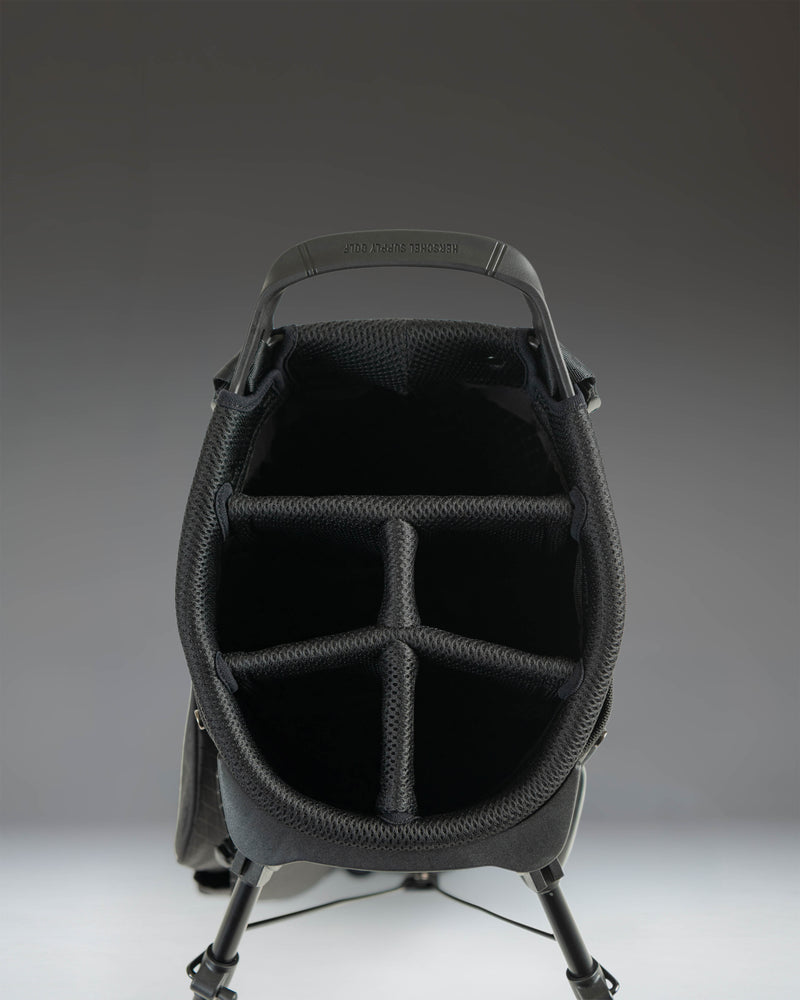 Herschel Watt Stand Bag in black, showing an oversized view of the golf bag's durable fabric, storage pockets, and sturdy stand mechanism.