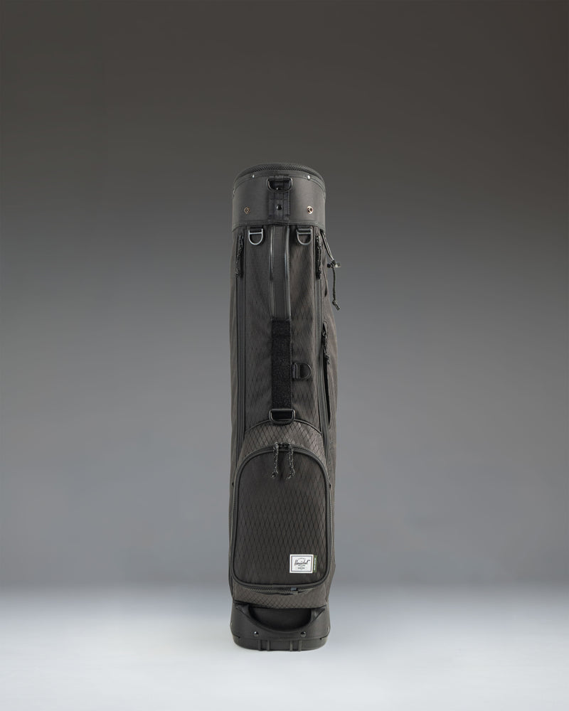 Black Herschel Watt Sunday Bag golf bag showing a side profile view with a carry strap and stand mechanism.