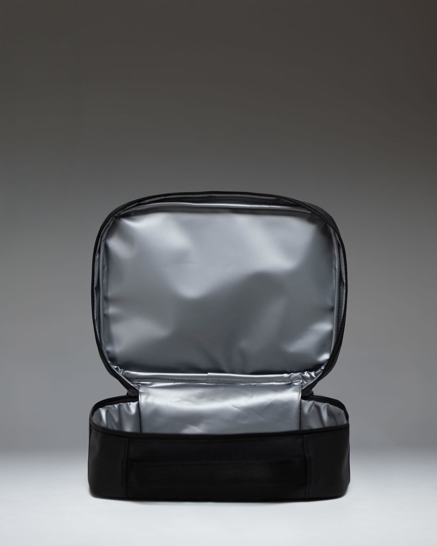 Herschel Supply Co. Pop Quiz Lunch Box in black, showing the insulated main compartment open with a mesh pocket on the inside lid.