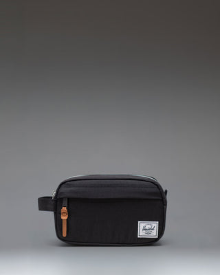Herschel Supply Co Chapter Small Travel Kit in black, showing the compact toiletry bag with its side handle and classic woven label.