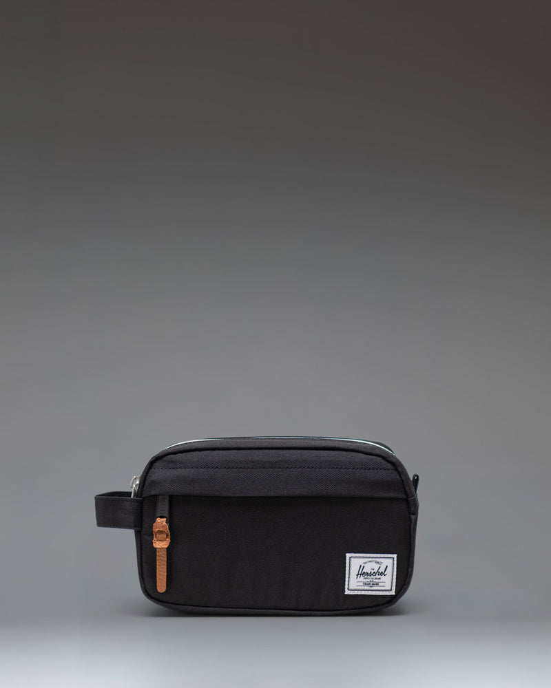 Herschel Supply Co Chapter Small Travel Kit in black, showing the compact toiletry bag with its side handle and classic woven label.